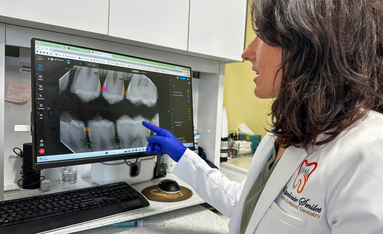 Dr. Aurora Dalipaj pointing to a digital dental X-ray on a monitor screen at Rittenhouse Smiles